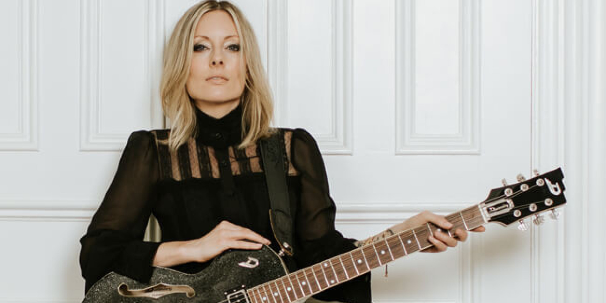 Christin Martin Deutschland Tournee Plakat für den 23.04.2026 im Schaukelpferd in Baiersbronn. Sie steht in schwarzen nSachen vor einer weißen Tür und hält eine schwarz braune E Gitarre in der Hand