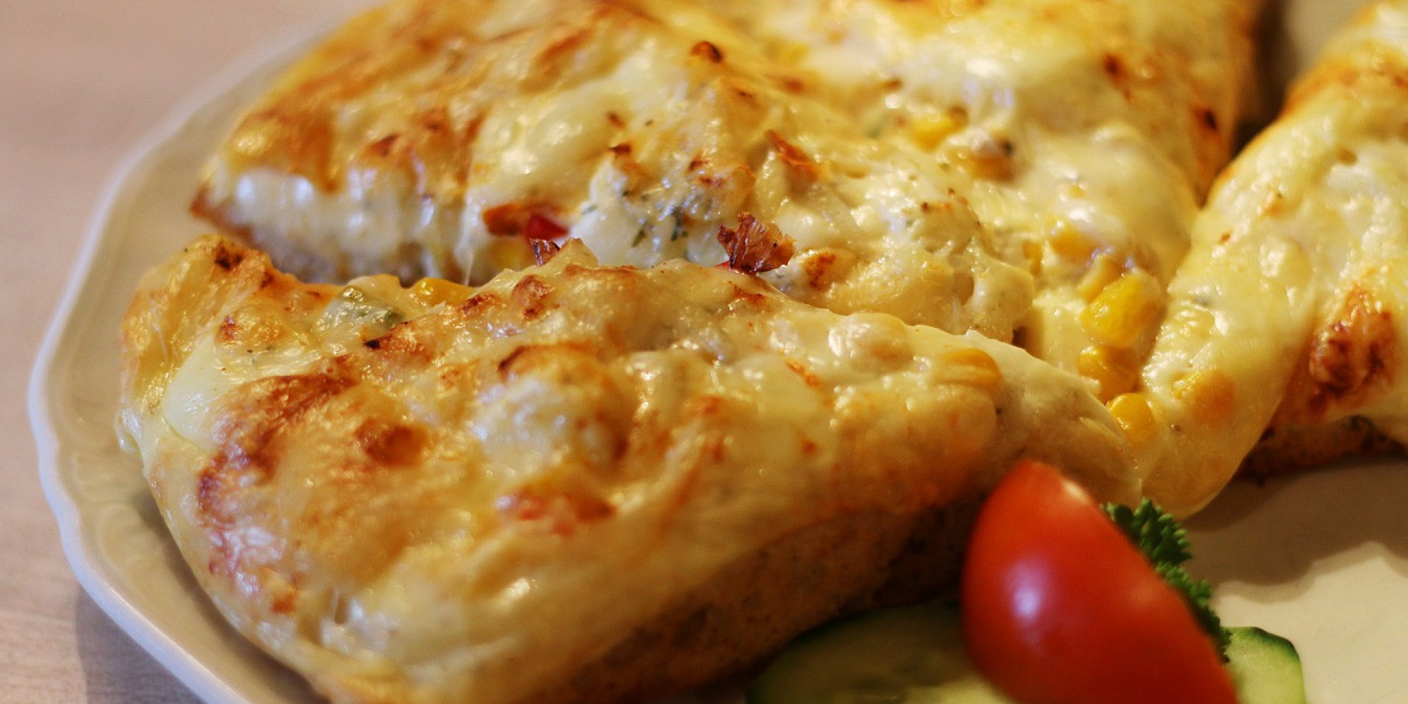 Knuspriges mit Käse überbackenes Fladenbrot dazu frische Tomaten und Gurkenscheiben.